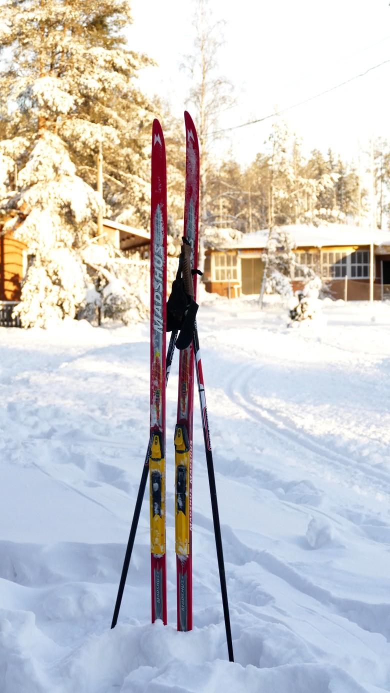 Sukset ja sauvat pystyssä hangessa