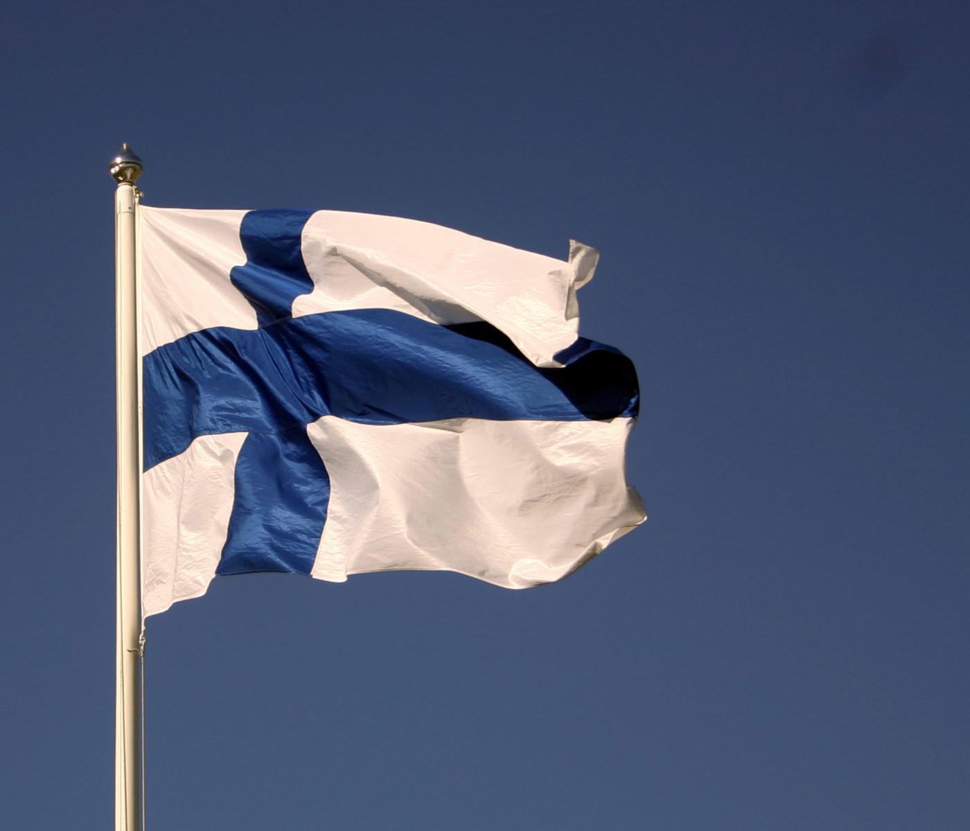 Suomen lippu liehuu salossa sinitaivaan alla.