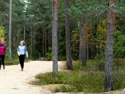 Kaksi naista kävelee syksyisellä ulkoiluradalla.