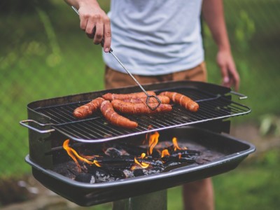 Henkilö grillaa grillissä makkaroita.