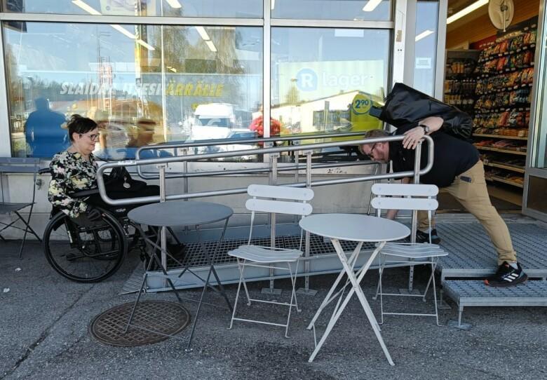 Pyörätuolilla liikkuva henkilö siirtymässä ramppia pitkin R-kioskin tilaan.