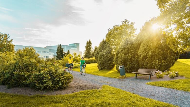 Kaksi pyöräilijää kesäisessä Hyvättylänpuistossa.