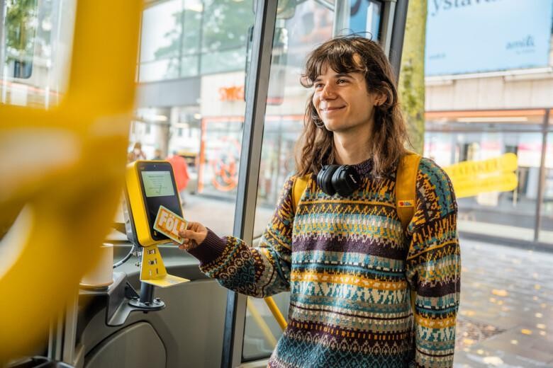 Hymyilevä nuori mies astuu Föli-bussiin ja maksaa matkan föli-kortilla.